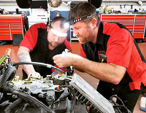 photo of 2 professional automobile mechanics repairing a car engine
